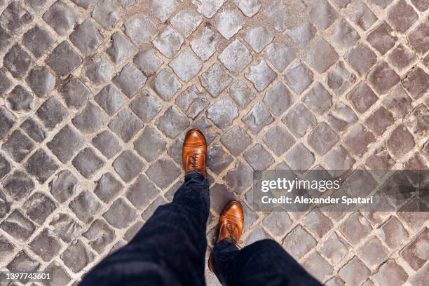 walking on cobblestone street wearing leather shoes in rome, directly above personal perspective view - shoes man foto e immagini stock