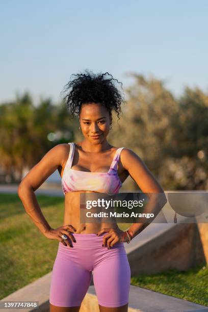 afro latin woman is outdoors doing physical exercises while looking at the camera that portrays her - african american women in the wind stock pictures, royalty-free photos & images