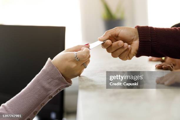 woman giving card to the clinic's receptionist - handing over credit card stock pictures, royalty-free photos & images