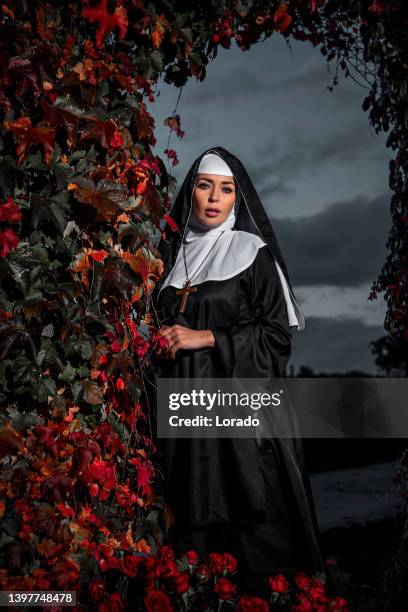 eine schöne brünette nonne in einem geheimen rosengarten - habit stock-fotos und bilder