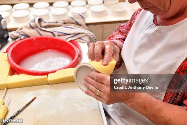 Joy Pass hollow ware sponges a saucer on May 17, 2022 in Stoke on Trent, England. Halcyon Days Ltd holds all three Royal Warrants to the British...