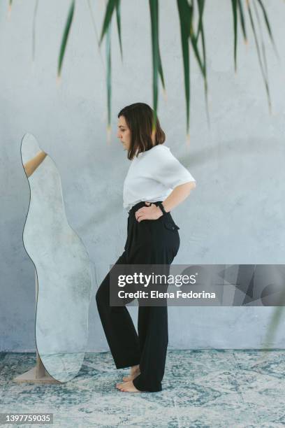 a young woman and the mirror. - woman-looking-into-mirror-full-body stock pictures, royalty-free photos & images