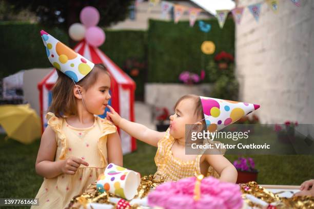 sisters having fun on a birthday party - eerste verjaardag stockfoto's en -beelden