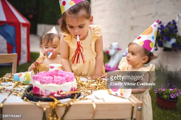 twin sisters with an older sister celebrating their first birthday - eerste verjaardag stockfoto's en -beelden