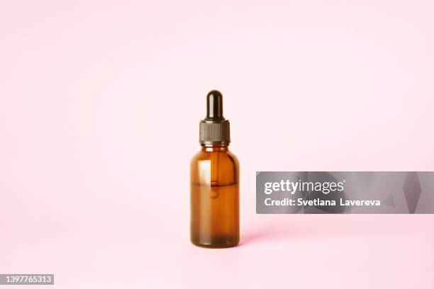 glass dropper bottle with a pipette with black rubber tip with many drops on it on the orange background. nature skin concept. organic spa cosmetics. trendy concept. front view. - dropper bottle stock pictures, royalty-free photos & images