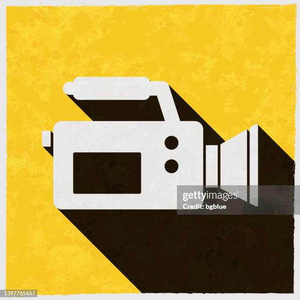 video camera. icon with long shadow on textured yellow background - gritty background texture stock illustrations