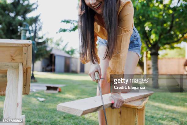 carpenter woman at work using saw to cut timber - hand saw stock pictures, royalty-free photos & images