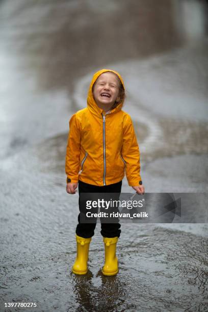 beine des kindes in gelben gummistiefelspringen in pfützen - girl wearing boots stock-fotos und bilder