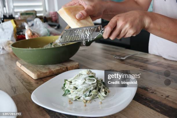 frau, die parmesan auf pasta legt - hartkäse stock-fotos und bilder