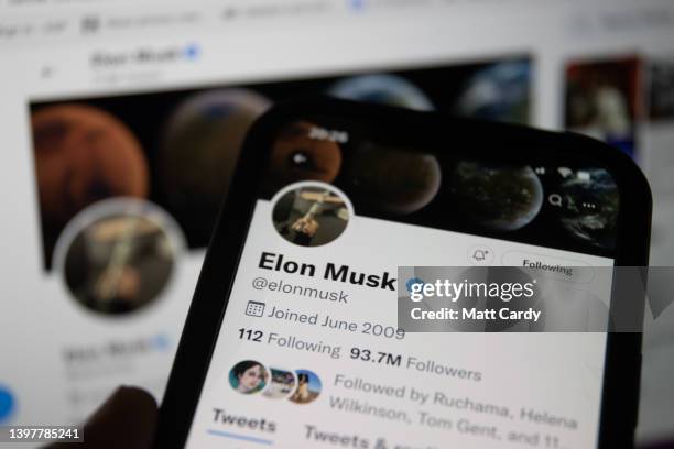 In this photo illustration a man looks at Elon Musk's Twitter account that is displayed on a smartphone screen on May 08, 2021 in Bristol, England....