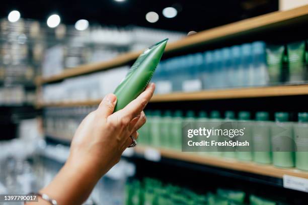 a close up view of an unrecognizable female's hand holding some beauty product - hygiene stockfoto's en -beelden