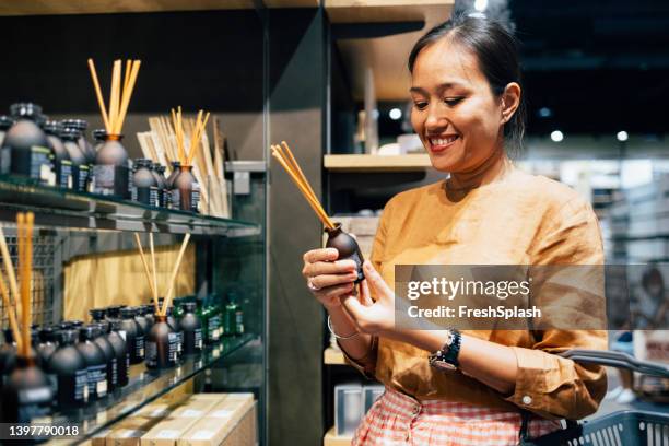 a happy woman holding essential oil sticks deciding whether to buy it or not - luftfräschare bildbanksfoton och bilder