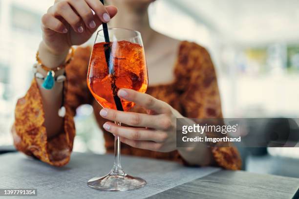 young woman enjoying italian cocktail spritz in restaurant. - drinking straw stock pictures, royalty-free photos & images