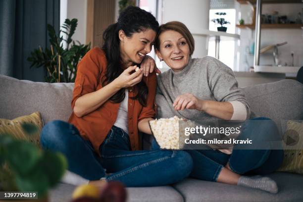 mutter und tochter schauen zusammen film und essen popcorn - realityserie stock-fotos und bilder