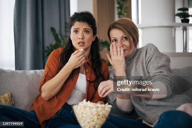 mother and daughter watching horror movie together and eating pop corns - 50 watching video stock pictures, royalty-free photos & images