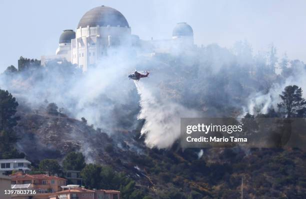 Firefighting helicopter performs a water drop over a brush fire near Griffith Observatory on May 17, 2022 in Los Angeles, California. The fire was...