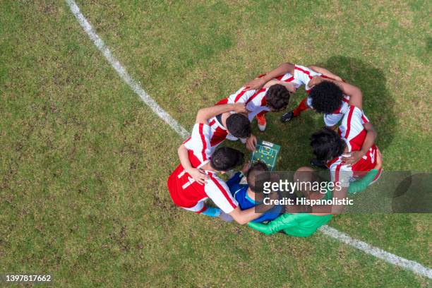 coach talking to a team of soccer player about their strategy for the game - soccer team stock pictures, royalty-free photos & images
