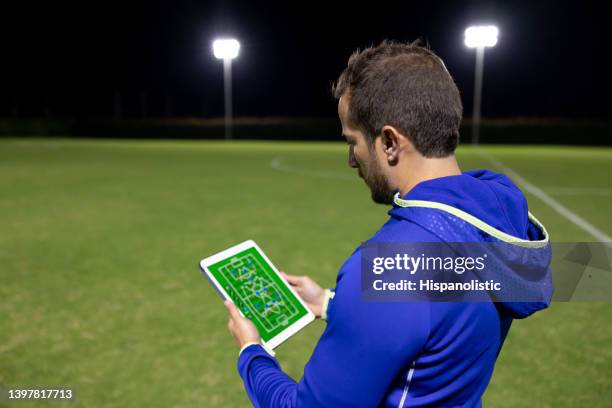 soccer coach looking at the lineup for a match on a tablet - sport tablet stockfoto's en -beelden