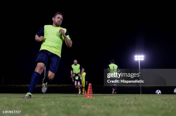 soccer team training at night and running between cones - sporthesje stockfoto's en -beelden