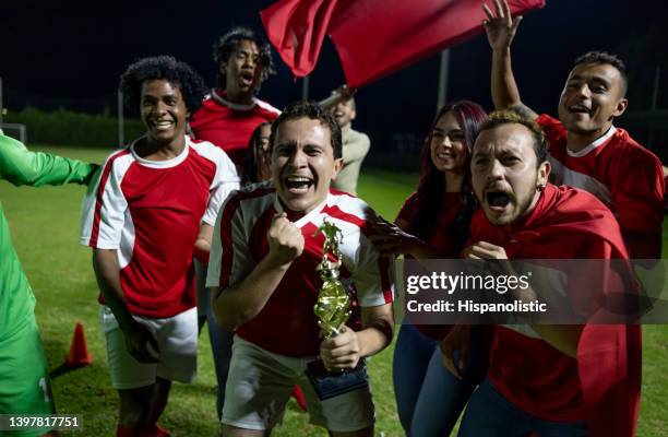 happy group of soccer players celebrating their win with their fans - football trophy stock pictures, royalty-free photos & images