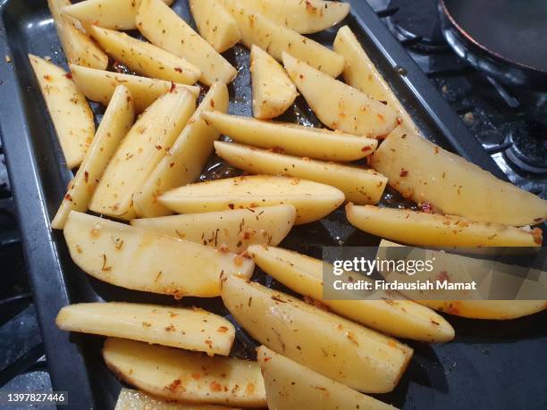 raw marinated  potatoes in baking tray - frite four photos et images de collection