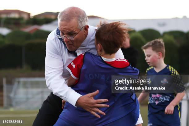 Prime Minister Scott Morrison accidentally knocks over a child during a visit to the Devonport Strikers Soccer Club, which is in the electorate of...