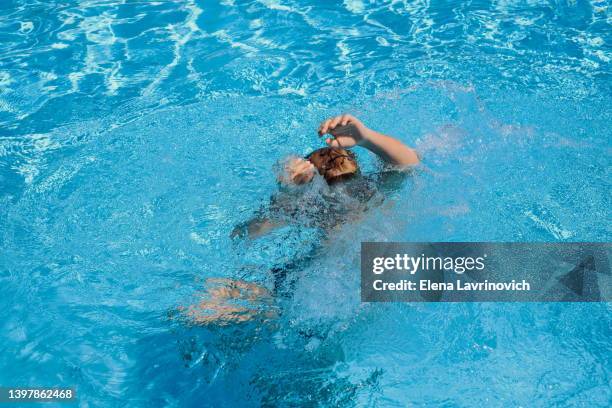 the child is drowning in the pool. drowning man. dangerous swimming. save a person - ahogar fotografías e imágenes de stock