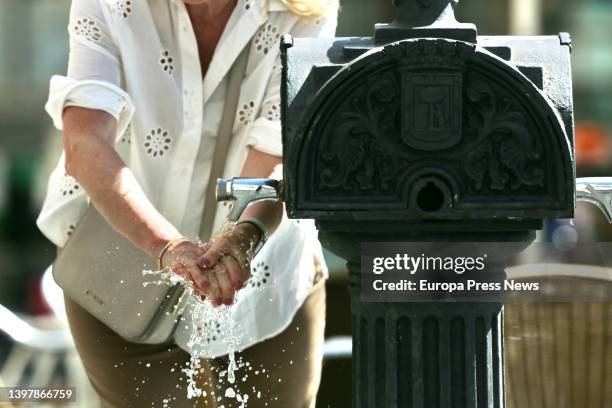 Woman washes her hands in a fountain on the day Spain will begin to experience a "major" hot spell with midsummer temperatures on May 17 in Madrid,...