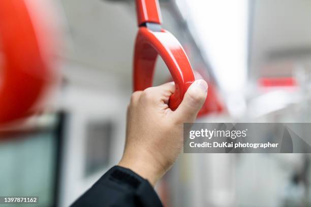 hand holding handle in subway - airport bus stock-fotos und bilder