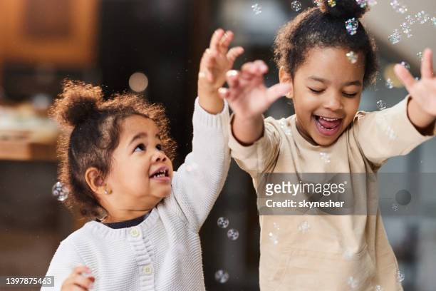 carefree african american girls catching bubbles at home. - catching bubbles stock pictures, royalty-free photos & images