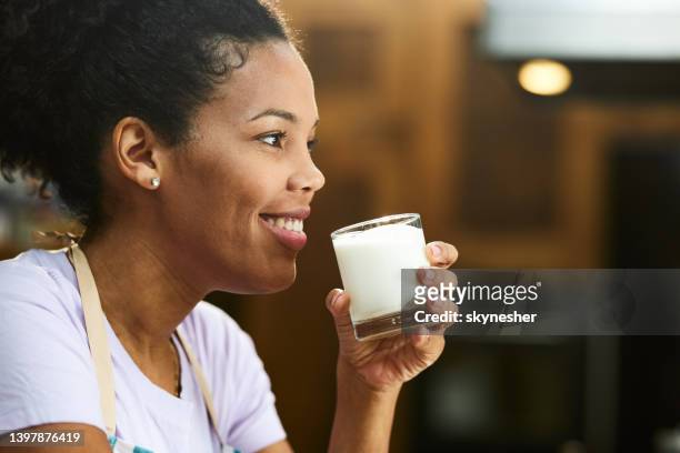 happy black woman drinking fresh milk at home. - woman drinking milk stock pictures, royalty-free photos & images