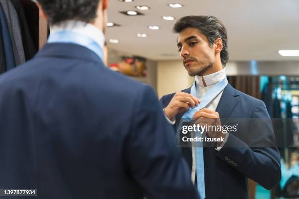 man looking at mirror reflection while wearing necktie - men fashion suit stock pictures, royalty-free photos & images