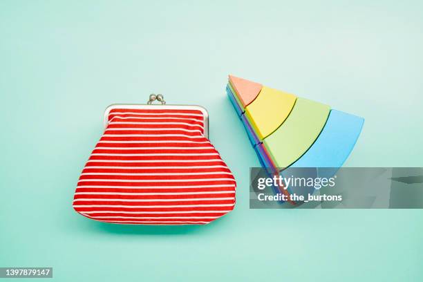 piece of pie chart made of colorful toy blocks and red wallet on turquoise background - multi colored purse stock-fotos und bilder