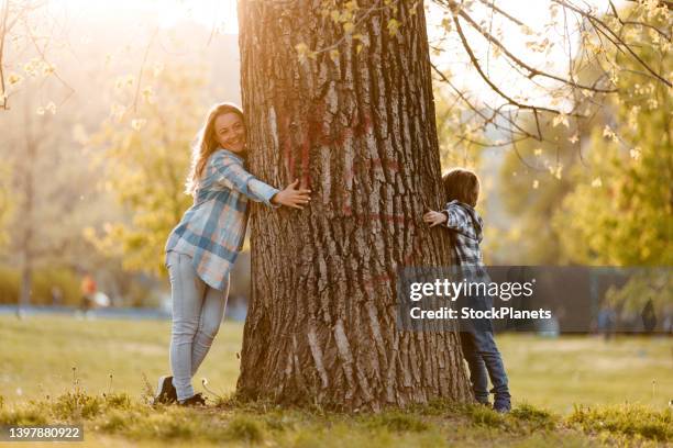 mother and son hugging a tree - tree hugging stock pictures, royalty-free photos & images