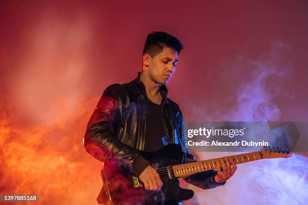portrait of a male guitarist enjoying playing the guitar in neon light in smoke with a copy of the space.concept music and advertising - musician male energy imagens e fotografias de stock