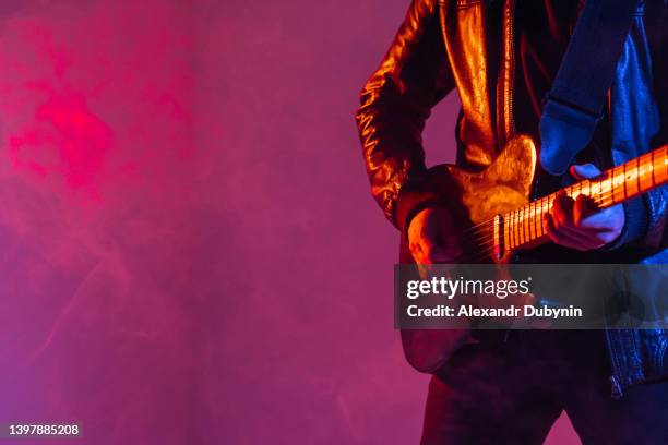 unrecognizable man guitarist plays music on the guitar on a colored background. - performer stock photos et images de collection