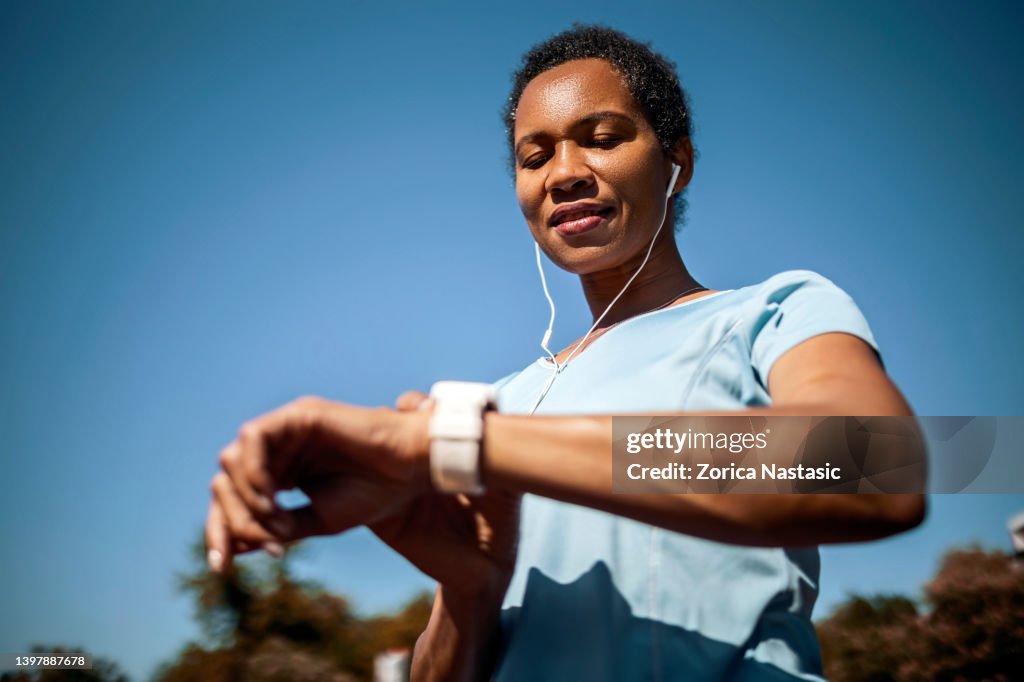 Femme souriante vérifiant la fréquence cardiaque après l’entraînement sportif