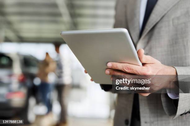 close up of a car salesperson working on digital tablet in a showroom. - car salesman stockfoto's en -beelden