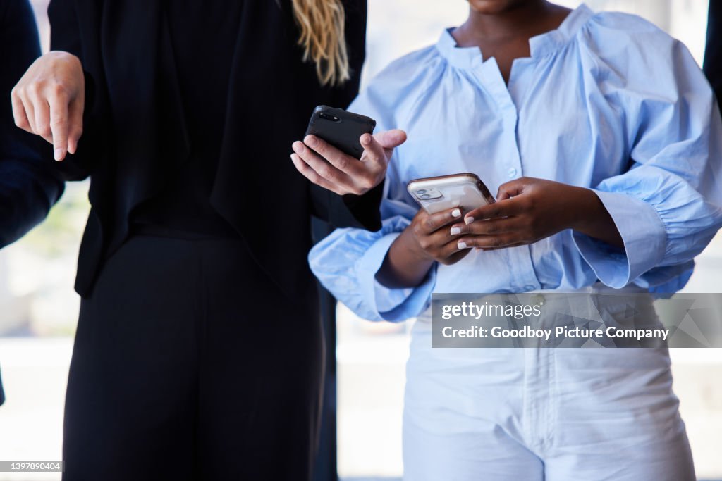 Two young businesswomen using smart phones in an office