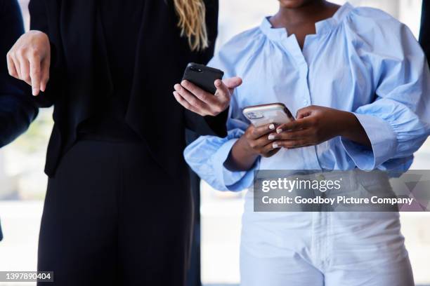 two young businesswomen using smart phones in an office - file sharing stock pictures, royalty-free photos & images