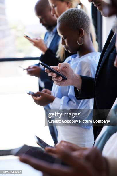 distracted businesspeople using smart phones while standing in an offfce - partilha de ficheiros imagens e fotografias de stock