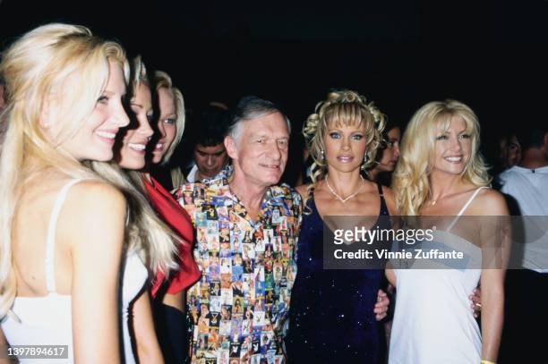 American magazine publisher Hugh Hefner , wearing a shirt featuring a collage of Playboy magazine covers, and Playboy models attend the Playboy Expo...