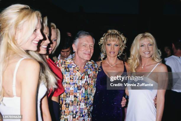 American magazine publisher Hugh Hefner , wearing a shirt featuring a collage of Playboy magazine covers, and Playboy models attend the Playboy Expo...