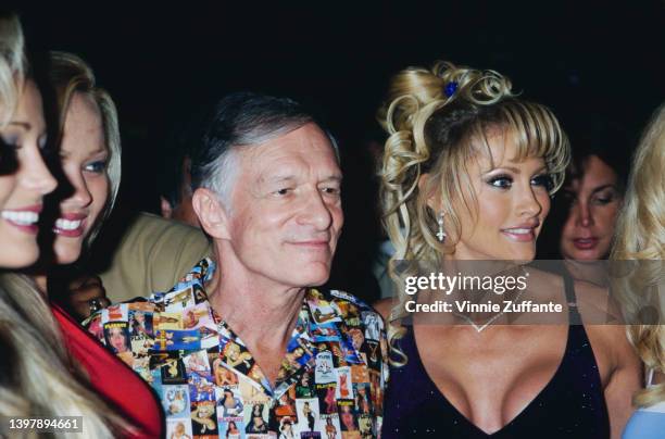 American magazine publisher Hugh Hefner , wearing a shirt featuring a collage of Playboy magazine covers, and Playboy models attend the Playboy Expo...