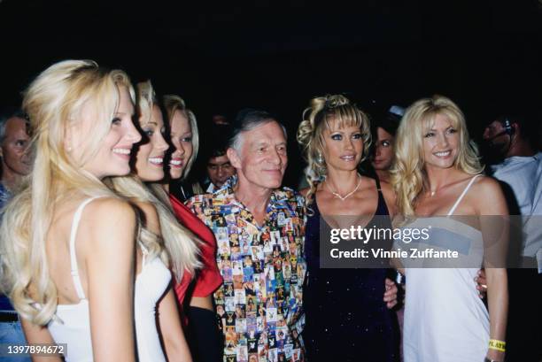 American magazine publisher Hugh Hefner , wearing a shirt featuring a collage of Playboy magazine covers, and Playboy models attend the Playboy Expo...