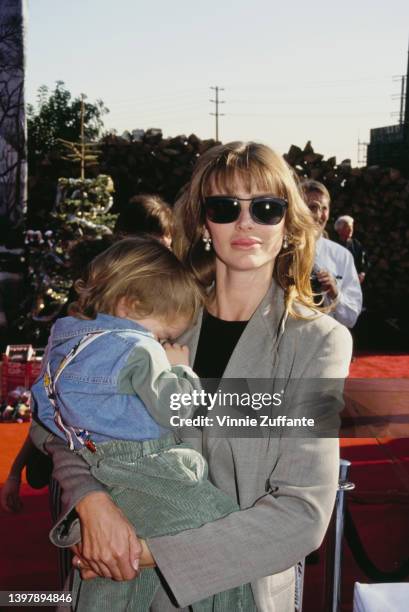 American model and actress Kimberley Conrad holding her son, Marston Hefner, attends the inaugural Spago Christmas Party for the 'Toys for Totskis...