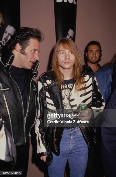 American comedian Andrew Dice Clay and American singer-songwriter Axl Rose, wearing a black leather jacket with a print of the torso of a human...