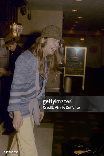 British singer and songwriter Ozzy Osbourne, wearing a blue striped cardigan with a brown hat, United States, circa 1980.