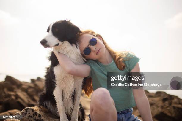 a young redhead girl posing with her dog on rocks  at the seaside - young teen girl beach ストックフォトと画像