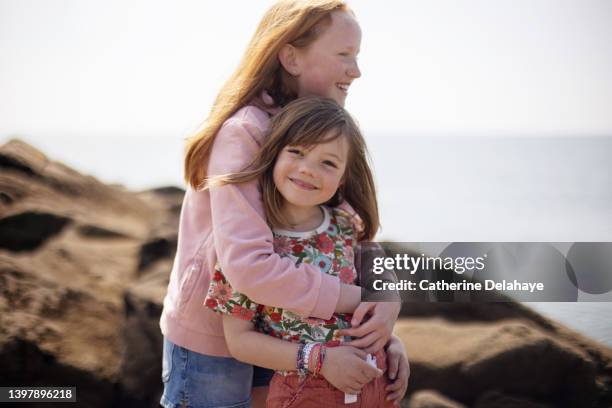 two smiling girls standing on the rocks - happy famille france photos et images de collection